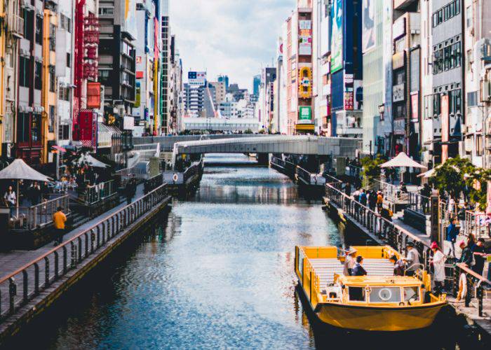 A boat waiting for passengers to embark along the Dotonbori River on a sunny day.